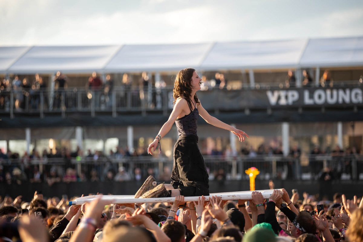 Girl crowdsurfing sitting on a toilet toi door at Rock For People
